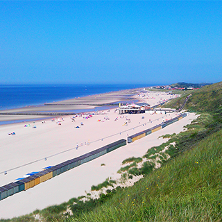 Het strand van Zoutelande met strandhokjes, blauwe lucht en Strandpaviljoen De Zeeuwse Riviera