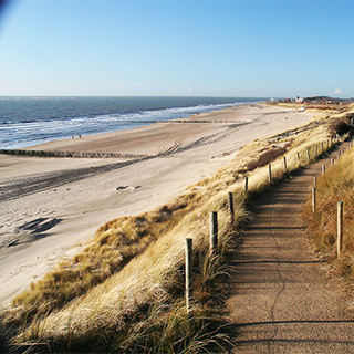 Mooi wandelpad en een stuimige zee, op de achtergrond de kerk van Zoutelande