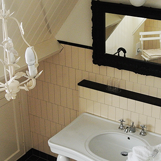 Kroonluchter, spiegel en de wasbak van de badkamer van kamer 3